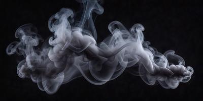 The primary subject of the image is a large, swirling cloud of smoke. The setting is a dark background, which contrasts with the smoke, making it the focal point of the image. The visual style is a black and white photo, giving the image a classic and timeless appearance. The colors and mood of the image are predominantly dark and moody, with the smoke creating a dramatic and mysterious atmosphere.