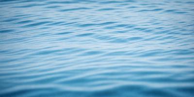 The primary subject of the image is a large body of blue water, which appears to be a lake or a large ocean. The water is calm and serene, with no visible waves or disturbances. The setting is a vast, open space, with no visible land or structures in the background. The visual style of the image is a close-up of the water, showcasing its depth and tranquility. The colors in the image are predominantly blue, creating a peaceful and soothing atmosphere.