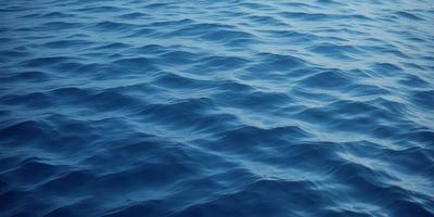 The primary subject of the image is a large body of blue water, which appears to be a deep blue ocean. The setting is a vast expanse of water, with no visible land or other objects in the background. The visual style of the image is a realistic representation of the ocean, with no indication of digital art or illustration. The dominant colors in the image are blue and white, creating a serene and calming atmosphere.