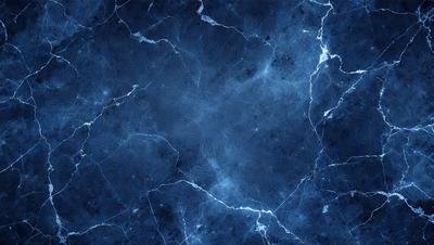 The primary subject of the image is a blue marble wall with a pattern of white and blue veins. The setting is a room with a blue tiled floor. The visual style is a close-up of the marble wall, showcasing the intricate vein patterns. The colors and mood of the image are predominantly blue, creating a calm and serene atmosphere.