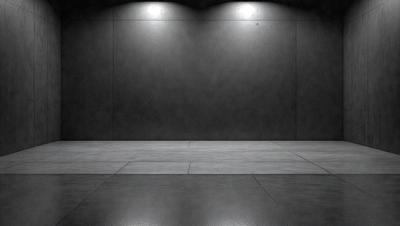 The primary subject of the image is a large, empty room with a concrete floor. The room appears to be a warehouse or a similar industrial space. The setting/background consists of a concrete wall, which is the main feature of the room. The visual style of the image is a black and white photo, giving it a classic and timeless appearance. The colors and mood of the image are predominantly dark, with the concrete wall and floor being the main focus.
