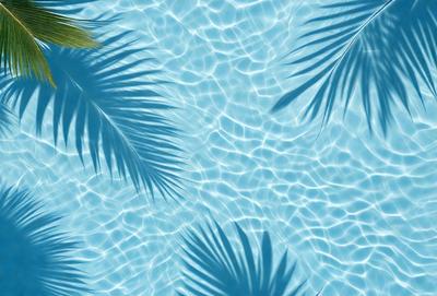 The primary subject of the image is a blue swimming pool filled with water. The pool is surrounded by palm trees, creating a tropical and relaxing atmosphere. The visual style of the image is a photo, capturing the natural beauty of the pool and the palm trees. The colors and mood of the image are predominantly blue and green, reflecting the calm and serene environment.