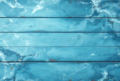 The primary subject of the image is a wooden plank with a blue marble-like surface. The setting is a room with a blue-toned wall, and the visual style is a close-up of the wooden plank. The colors and mood of the image are predominantly blue, creating a calm and serene atmosphere.