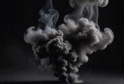 The primary subject of the image is a large, dark, and smoky cloud. The setting is a dark background, which contrasts with the cloud, creating a dramatic visual effect. The visual style is a black and white photo, which adds to the mood of the scene. The colors and mood of the image are dark and moody, with the cloud being the main focus and dominating the entire image.