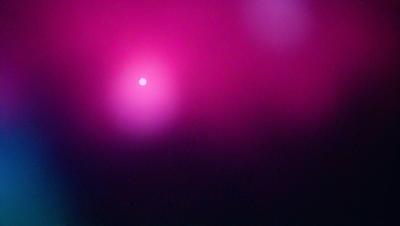 The primary subject of the image is a bright pink sun, which is the main focus of the scene. The setting is a dark purple background, creating a contrasting and dramatic effect. The visual style appears to be a photo, capturing the sun's rays and the vibrant color of the pink sky. The colors and mood of the image are bold and striking, with the pink sun and purple background creating a striking contrast and a sense of intensity.