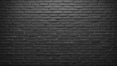 The primary subject of the image is a brick wall. The setting is a dark room, and the visual style is a black and white photo. The dominant colors are black and white, creating a moody atmosphere.