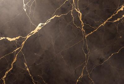 The primary subject of the image is a marble countertop with a gold-colored design. The setting is a kitchen, and the visual style is a close-up of the marble countertop. The colors and mood of the image are predominantly dark, with the gold accents adding a touch of warmth and sophistication.
