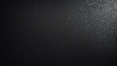 The primary subject of the image is a black background with a few white specks. The setting is a dark room, and the visual style is a black and white photo. The dominant colors are black and white, and the overall atmosphere is moody and dramatic.
