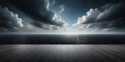 The primary subject of the image is a pier extending out over the ocean. The setting is a cloudy day, with a blue sky visible in the background. The visual style is a black and white photo, which adds a sense of timelessness and nostalgia to the scene. The colors and mood of the image are predominantly dark and moody, with the pier and ocean serving as the main focal points.