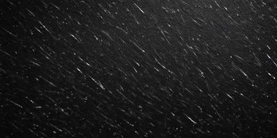 The primary subject of the image is a black background with a few white streaks. The setting is a night sky, and the visual style is a black and white photo. The colors and mood of the image are predominantly dark and moody, with the white streaks adding a touch of brightness.