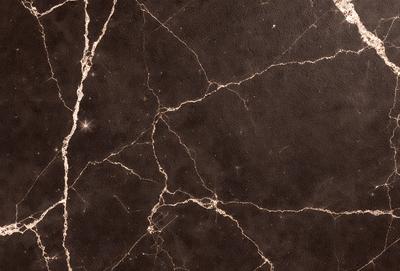 The image features a black marble countertop with a pattern of holes and bumps. The countertop appears to be a part of a wall, and the surface is textured, giving it a unique and interesting appearance. The overall atmosphere of the image is dark and moody, with the black marble countertop being the primary subject.