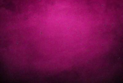 The primary subject of the image is a large, pink, textured surface. The setting is a dark, purple background, which contrasts with the pink surface. The visual style appears to be a photo, as the image is described as a "pink photo." The dominant colors are pink and purple, creating a warm and vibrant atmosphere.