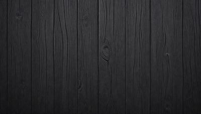 The primary subject of the image is a wooden wall with a black surface. The setting is a room with a black wall, and the visual style is a close-up of the wooden wall. The colors and mood of the image are predominantly black, giving it a dark and moody atmosphere.