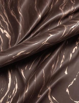 The primary subject of the image is a piece of fabric, which is the main object, scene, or focus of the image. The setting or background is a dark room, and the visual style is a close-up of the fabric. The colors and mood of the image are predominantly dark, with the fabric being the main source of visual interest.