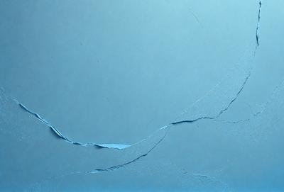 The primary subject of the image is a blue wall with a crack in it. The setting is a room with a blue background. The visual style is a photo of the cracked wall. The dominant colors are blue and white, creating a calm and soothing atmosphere.