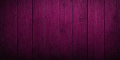 The primary subject of the image is a wooden wall with a purple color. The setting is a room with a wooden floor. The visual style is a close-up of the wooden wall, showcasing its texture and color. The dominant colors are purple and brown, creating a warm and cozy atmosphere.