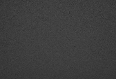 The primary subject of the image is a black surface, which appears to be a wall or a piece of fabric. The setting is a dark room, and the visual style is a close-up of the black surface. The colors and mood of the image are predominantly dark and moody, with the black surface being the main focus.