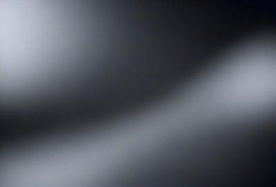 The primary subject of the image is a light source, which is creating a shadow on a wall. The setting is a dark room, and the visual style appears to be a photo. The dominant colors in the image are black and white, giving it a moody and dramatic atmosphere.