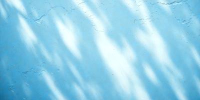The primary subject of the image is a blue surface with shadows and reflections. The setting is a body of water, possibly a lake or a river, with trees in the background. The visual style is a combination of a photo and digital art, creating a unique and artistic representation of the scene. The colors and mood are predominantly blue, with some white and gray tones, giving the image a calm and serene atmosphere.