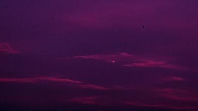 The primary subject of the image is a purple sky with clouds. The setting is a cloudy sky, and the visual style is a photo. The colors and mood of the image are predominantly purple, creating a serene and calming atmosphere.