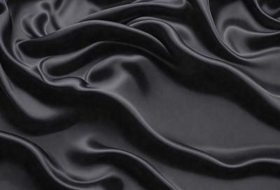 The primary subject of the image is a close-up of a black fabric, possibly a piece of leather or a silk material. The setting is a dark background, which emphasizes the fabric's texture and appearance. The visual style is a close-up, focusing on the details of the fabric. The colors and mood of the image are predominantly dark, with the black fabric being the main focus.