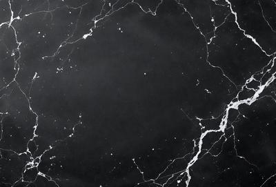 The primary subject of the image is a black marble countertop. The setting is a dark room, and the visual style is a close-up of the marble countertop. The countertop appears to be a dark grey color, giving it a somewhat moody atmosphere.