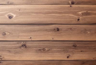 The primary subject of the image is a wooden wall with a wooden texture. The setting is a room with a wooden floor. The visual style is a close-up of the wooden wall, showcasing its texture and details. The colors and mood of the image are warm and natural, with the wooden elements creating a cozy and rustic atmosphere.
