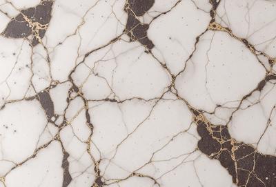 The primary subject of the image is a marble-like surface with a gold-like pattern. The setting is a white marble countertop, and the visual style is a close-up of the marble pattern. The colors and mood of the image are predominantly white and gold, giving it a luxurious and elegant appearance.