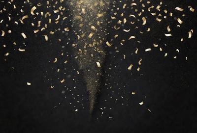 The primary subject of the image is a gold confetti explosion. The setting is a black background, which contrasts with the gold confetti. The visual style is a digital art or illustration, creating a dynamic and eye-catching scene. The colors and mood are predominantly gold and celebratory, evoking a sense of joy and festivity.