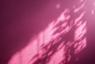 The primary subject of the image is a pink sky with clouds. The setting is a cloudy sky, and the visual style appears to be a photo. The dominant colors are pink and purple, creating a warm and serene atmosphere.