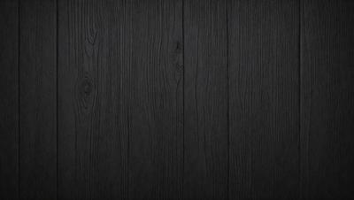 The primary subject of the image is a wooden floor. The setting is a dark room, and the visual style is a black and white photo. The colors and mood of the image are predominantly dark, creating a moody atmosphere.