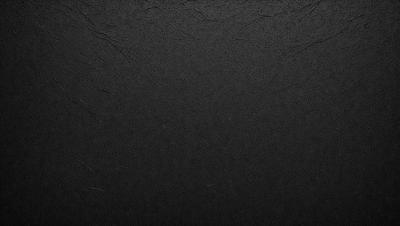 The primary subject of the image is a black background with a texture that resembles a wall or a piece of fabric. The setting is a dark room, and the visual style appears to be a close-up of the black background. The colors and mood of the image are predominantly dark and moody, with the black background being the main focus.