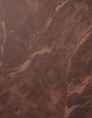 The primary subject of the image is a brown leather surface with a patterned texture. The setting is a room with a wooden floor, and the visual style is a close-up of the leather surface. The colors and mood of the image are warm and earthy, with the brown leather being the dominant color.