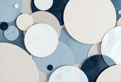 The primary subject of the image is a collection of white and blue marble circles. These circles are arranged in various sizes and are placed on a blue and white background. The visual style of the image is a combination of photo and digital art, creating a unique and eye-catching pattern. The dominant colors in the image are white and blue, giving the scene a clean and sophisticated appearance.