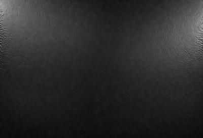 The primary subject of the image is a black leather surface. The setting is a dark room, and the visual style is a close-up of the leather surface. The colors and mood of the image are predominantly dark and moody, with the black leather being the main focus.