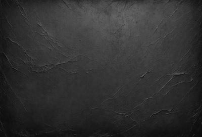 The primary subject of the image is a black leather surface. The setting is a dark room, and the visual style is a close-up of the leather surface. The colors and mood of the image are predominantly dark and moody, with the black leather serving as the focal point.