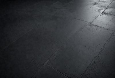 The primary subject of the image is a black and white photo of a floor. The setting is a dark room with a concrete floor. The visual style is a black and white photo, which gives the image a classic and timeless appearance. The colors and mood of the image are predominantly dark and moody, with the black and white color scheme adding to the overall atmosphere.