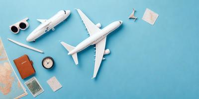 The primary subject of the image is a white model airplane, which is placed on a blue surface. The setting appears to be a workspace or a display area, as there are several other objects around the airplane. These objects include a clock, a tie, a suitcase, and a book. The visual style of the image is a combination of photo and digital art, creating a unique and interesting display. The colors and mood of the image are predominantly blue and white, giving it a clean and professional appearance.