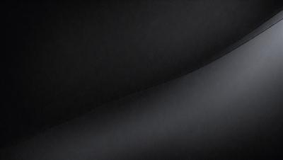 The primary subject of the image is a black background with a gray surface. The setting is a dark room, and the visual style is a close-up of the gray surface. The colors and mood of the image are predominantly dark and moody, with the gray surface being the main focus.