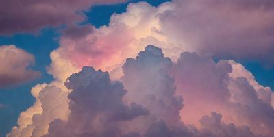 The primary subject of the image is a cloudy sky with a pink and blue hue. The setting is a cloudy day, and the visual style is a painting. The colors and mood of the image are vibrant and serene, creating a beautiful and peaceful atmosphere.