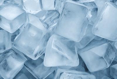 The primary subject of the image is a large pile of ice cubes. The ice cubes are blue and are arranged in a stack, creating a visually appealing scene. The setting is a kitchen, with the ice cubes placed on a counter. The visual style is a photo, capturing the details and colors of the ice cubes. The dominant colors are blue, and the overall atmosphere is cool and refreshing, as the ice cubes are a common symbol of cold weather and summer drinks.