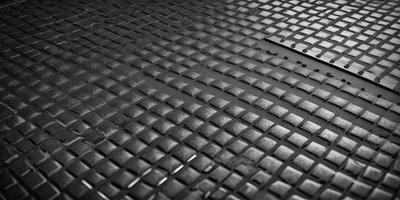 The primary subject of the image is a black leather surface, which appears to be a leather-like material or a leather-like pattern. The setting is a black background, which contrasts with the leather surface. The visual style is a close-up of the leather surface, showcasing its texture and pattern. The colors and mood of the image are predominantly black, giving it a sleek and modern appearance.