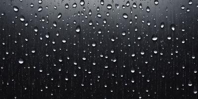 The primary subject of the image is a rainy day, as evidenced by the raindrops falling on a black surface. The setting is outdoors, with the raindrops falling on a black background. The visual style is a close-up of the raindrops, creating a moody and atmospheric scene. The colors are predominantly black and white, with the raindrops being the main focus of the image.