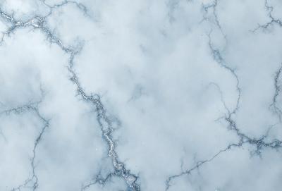 The image features a marble-like surface with a cloudy, blue-gray sky as the background. The primary subject is a close-up of the marble, showcasing its intricate texture and patterns. The visual style is a combination of a photo and digital art, creating a unique and captivating scene. The colors and mood of the image are predominantly blue and gray, giving it a calm and serene atmosphere.