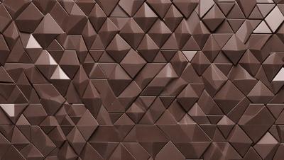 The primary subject of the image is a brown brick wall with a unique pattern of triangular shapes. The setting is a room with a brown brick wall as the main focus. The visual style is a close-up of the brick wall, showcasing the intricate pattern of the triangular shapes. The colors and mood of the image are warm and earthy, with the brown brick wall serving as the main visual element.