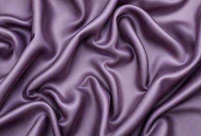 The primary subject of the image is a close-up of a purple fabric, showcasing its texture and details. The setting is a room with a purple background, which complements the purple fabric. The visual style is a close-up of the fabric, emphasizing its texture and appearance. The colors and mood of the image are predominantly purple, creating a calm and soothing atmosphere.