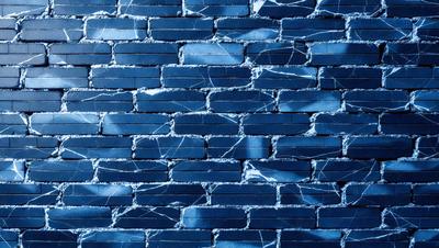 The primary subject of the image is a blue brick wall. The setting is a brick wall with a blue tint, and the visual style is a close-up of the brick wall. The colors and mood of the image are predominantly blue, creating a calm and serene atmosphere.