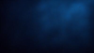 The primary subject of the image is a dark blue sky with a few clouds. The setting is a vast, open space, and the visual style is a photo. The colors and mood of the image are predominantly dark and moody, with the blue sky and clouds creating a dramatic atmosphere.