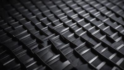 The primary subject of the image is a close-up of a black and grey patterned surface, which appears to be a textured material or a patterned fabric. The setting is a dark room, and the visual style is a close-up of the patterned surface. The colors and mood of the image are predominantly dark and moody, with the black and grey patterned surface being the main focus.