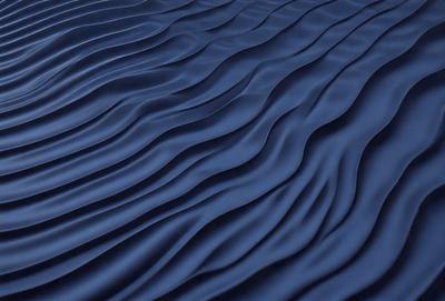 The primary subject of the image is a blue, rippled surface, which appears to be a piece of fabric or a digital artwork. The setting is a blue background, and the visual style is a digital artwork or a photo with a blue tint. The colors and mood of the image are predominantly blue, creating a calm and serene atmosphere.